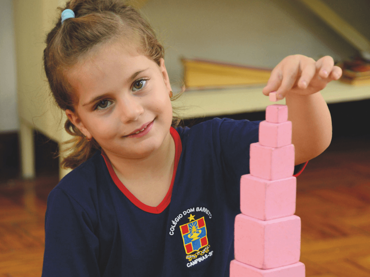 Aluna manuseando material sensorial Montessori (torre rosa)